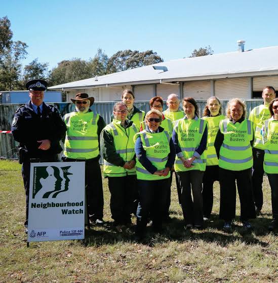 Volunteers and authority representatives standing smiling with yellow and blue uniforms. 